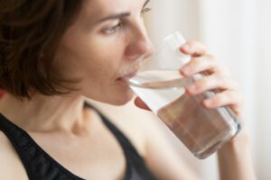 Kvinna som dricker ett glas vatten efter träning